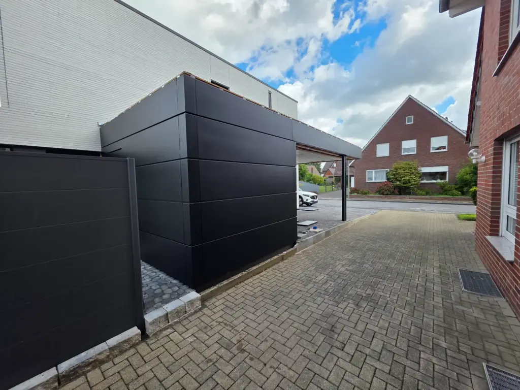 Anthrazitfarbene Aluminiumfassade an einem kompakten Anbau mit Carport