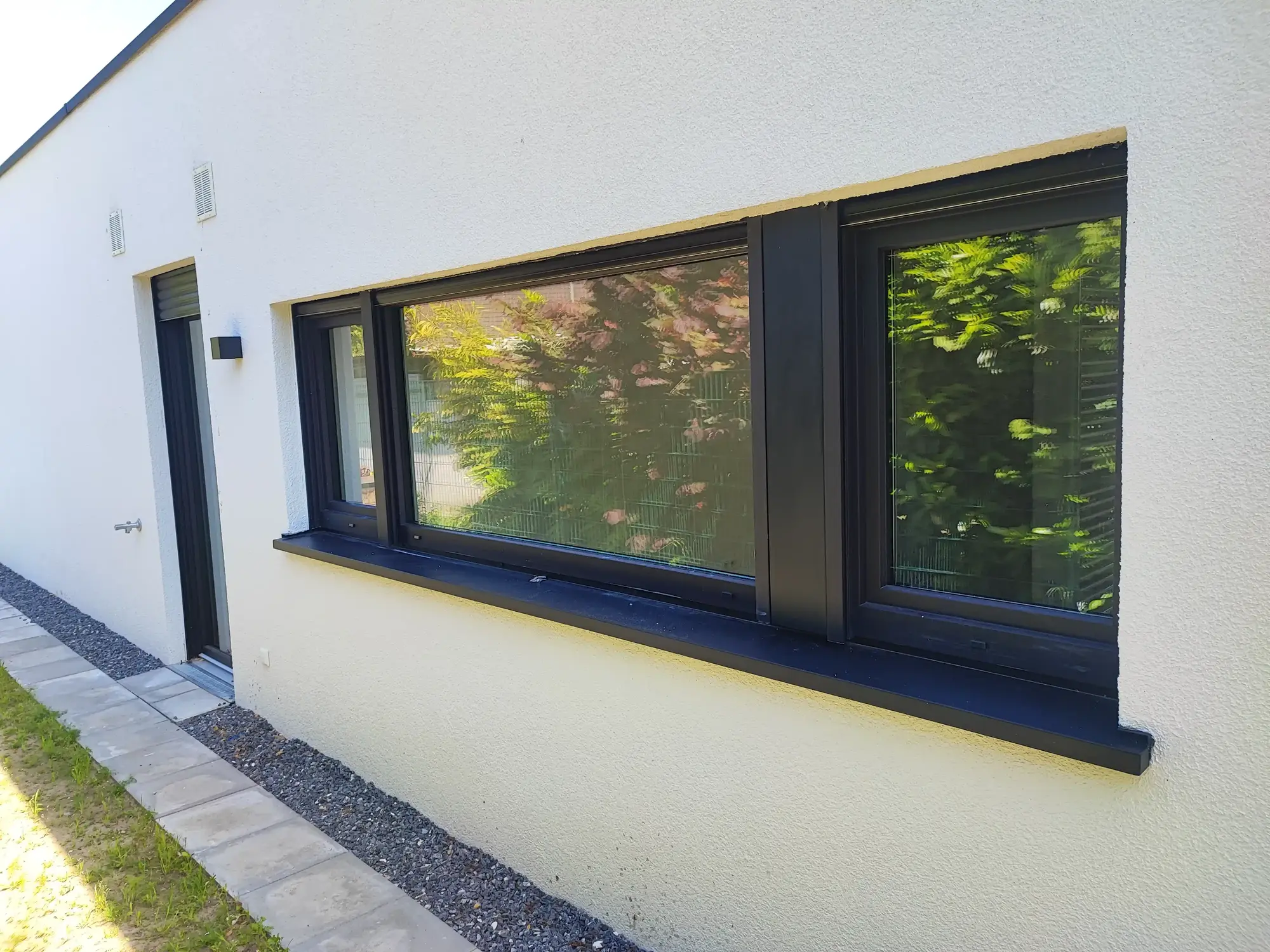 Maßgefertigte Aluminiumfensterbank mit seitlichen Anschlüssen an einer Fassade